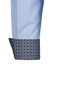 Manica di camicia azzurra chiara con polsino a motivo navy contrastante caratterizzato da disegni geometrici azzurri. Tessuto liscio e forma strutturata.
