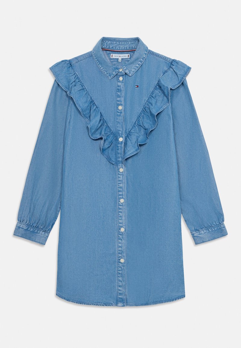 Camisa de ganga azul clara com mangas longas, fecho de botões e gola ondulada. Apresenta um pequeno detalhe de logótipo no lado esquerdo do peito.