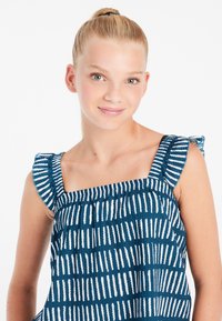 Mėlyna be rankovių palaidinė su baltais vertikaliais dryžiais, tekstūruotas audinys, kvadratinis iškirpimas ir raukšlėti peties akcentai. Tinkama šiltam orui.