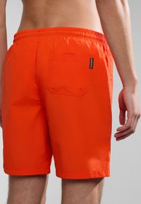 Oranžové plavecké šortky z lehkého materiálu, s elastickým pasem, zadní kapsou a krátkým lemem. Texturovaný povrch.