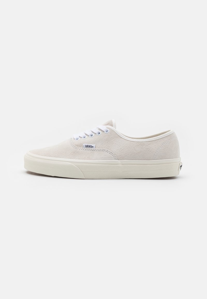Baskets Vans blanches en daim, avec un design à tige basse, un bout arrondi, des lacets blancs et une semelle en caoutchouc avec un logo signature sur le côté.