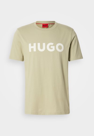 Тениска от памук в маслинено зелено с кръгло деколте и смело бяло лого "HUGO" отпред. С къси ръкави, без видими шарки или акценти.