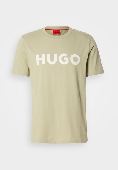Тениска от памук в маслинено зелено с кръгло деколте и смело бяло лого "HUGO" отпред. С къси ръкави, без видими шарки или акценти.