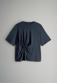 Tumed sinine T-särk, lühikeste varrukatega, ümmargune kaelus, millel on ees keeratud sõlm, valmistatud pehmest ja siledast kangast.