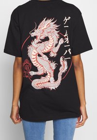 Černé tričko s detailním designem červeného a bílého draka na zádech, s japonským textem a kruhovými akcentovými prvky.