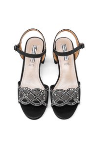 Sandali neri in suede con tacco alto, caratterizzati da un design a strisce incrociate e dettagli argentati sopra le dita. Include una cinghietta regolabile alla caviglia.