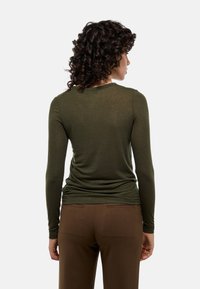 Haut à manches longues olive avec un col rond et une coupe ajustée, associé à un pantalon marron avec des poches arrière. Tissu doux et léger.