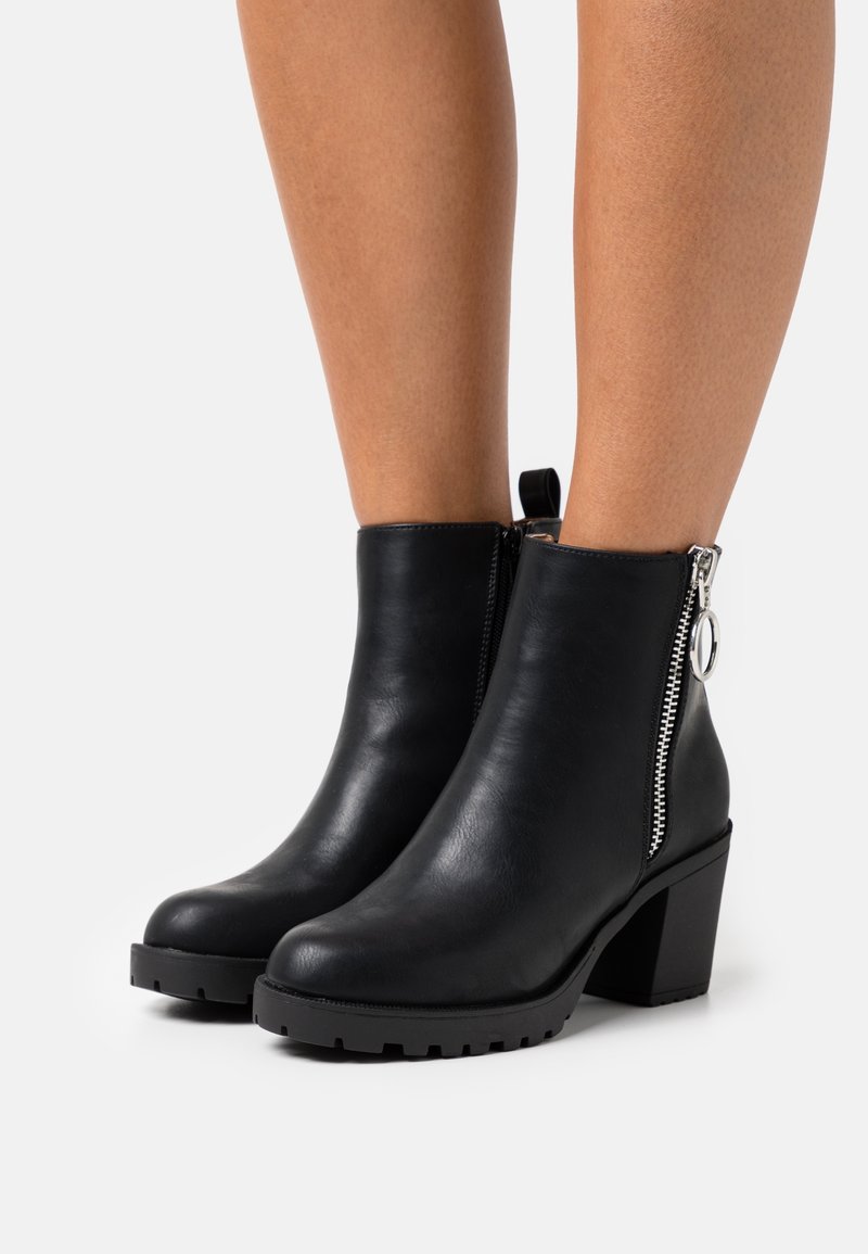 Black leather ankle boots with a chunky heel, side zipper detail, rubber lug sole, and pull tab at the back for easy wear.