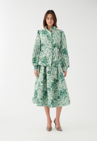 Roheline lilleline kleit, pikkade puffsleevedega, vöödiga taljes ja kihilise seelikuga. Valmistatud tekstureeritud kangast. Elegantne disain.