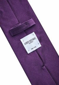 Lila slips med en diagonal ruggad textur. Har en vit etikett med "JOHN HENRIC SWEDEN" och "Made in Italy" tryckt i svart.