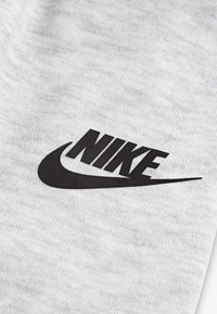 Grauer Stoff mit einem strukturierten Muster und einem auffälligen schwarzen Nike-Logo in der Mitte, gestaltet mit sanften, geschwungenen Kanten.