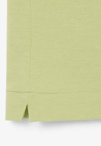 Lichtgroene geweven stof met een gestikte zoom en een klein schuine splitdetail aan de onderrand.