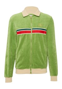 Zöld velúr cipzáras dzseki krémszínű bordával és mandzsettával, vízszintes piros és kék csíkos mintával a mellkason. Arany logó részlet.