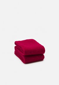 Paire de chaussettes épaisses en laine rouge foncé, pliées, sur fond blanc.