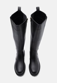 Ein Paar hohe schwarze Lederstiefel mit runden Zehen, seitlichen Reißverschlüssen und Zuglaschen auf weißem Hintergrund, von oben betrachtet.