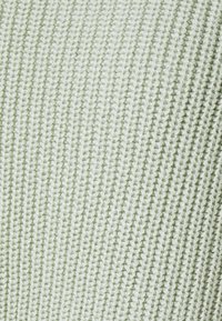 Vaaleanvihreä neulottu kangas, jossa on poikittaiset kohokuvioidut pystysuorat viivat ja pehmeä, sileä pinta.