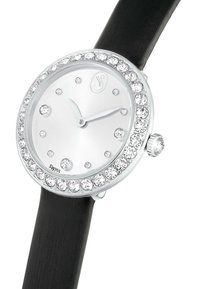 Reloj plateado con bisel adornado con piedras de imitación, esfera blanca y correa de caucho negro. Cuenta con marcadores de hora y una corona en el lateral.