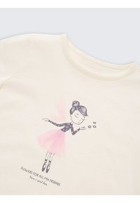 Lichtgekleurde katoenen t-shirt met een ronde halslijn. Bevat een bedrukte illustratie van een meisje in een blauwe outfit en een roze rok, die bloemen blaast.