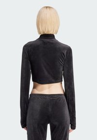 Sort cropped langærmet top i blødt velourmateriale, med en mock-neck og matchende høj talje bukser, der har en glat tekstur.