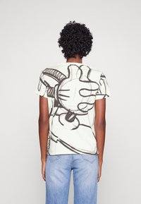 Lys grøn bomulds T-shirt med en stor sort grafisk illustration på ryggen. Korte ærmer, standard pasform og rund halsudskæring.