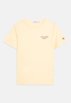 Lysegul T-shirt med korte ærmer med teksten "Calvin Klein Jeans" på brystet og lille "ck" logo på venstre ærme, rundhals stil.