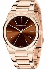 Montre ronde avec un boîtier octogonal en or rose et un cadran brun foncé. Présente des index horaires métalliques et un bracelet à maillons. Logo LIEBESKIND visible.