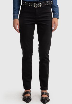 Zwarte slim-fit jeans met een gladde textuur, voorzien van een medium taille, gecombineerd met een zwarte riem versierd met zilveren studs.
