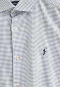 Camicia a quadri grigio chiaro con bottoni bianchi e logo ricamato blu navy. Tessuto in cotone con una texture liscia. Design del colletto classico.