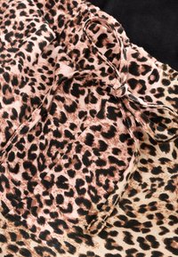 Tkanina s uzorkom leoparda u ružičastim i crnim nijansama, s detaljem mašne i glatkom teksturom, uglavnom s svijetlom podlogom.