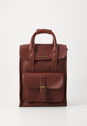 Sac à dos en cuir marron avec une surface texturée, une poignée supérieure et une poche avant sécurisée par une boucle. Logo doré et accents de couture.