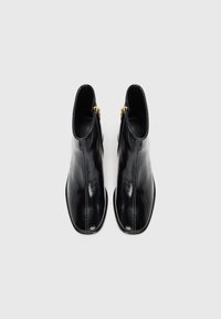 Botine negre din piele, cu un finisaj neted, vârf ascuțit și accente de fermoar aurii pe lateral. Talpă plată, design elegant.