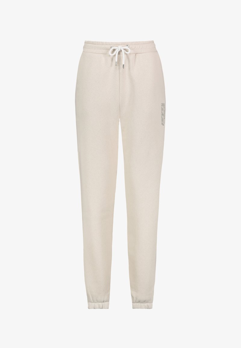 Beige cotton sweatpants with elastic waistband, drawstring, and ribbed cuffs. Features printed text detail on the side.