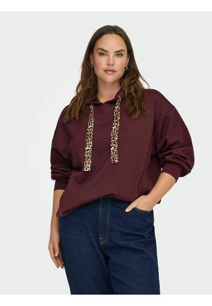 Burgundijas kapuca ar leoparda rakstu saites, brīvs piegriezums, organiskā kokvilna un garās piedurknes, saskaņota ar tumši ziliem džinsiem.