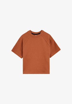 Haut tricoté à manches courtes de couleur orange rouille avec col rond et manches raglan, présenté à plat sur un fond blanc.