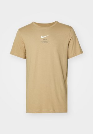 Šviesiai ruda trumpomis rankovėmis medvilninė marškinėliai. Puošia baltas Nike logotipas ir juoda spausdinta užrašas. Apvalus iškirpimas, laisvas siluetas ir standartinė ilgis.
