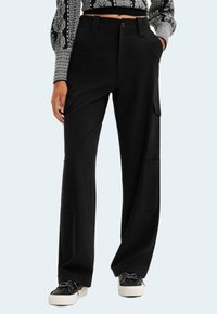 Black cargo pants with wide legs, featuring side pockets, a button closure, and belt loops. Smooth fabric with a matte finish.