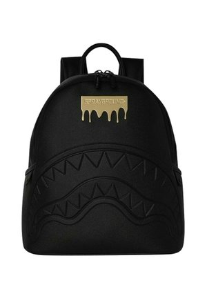 Zaino nero con motivo a denti di squalo in rilievo sul davanti e patch dorato con effetto goccia e scritta "Sprayground" in alto al centro.