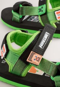 Zwarte en groene sandalen met verstelbare bandjes, voorzien van een Minecraft-personage accent en gevoerde binnenzolen, geschikt voor jonge dragers.