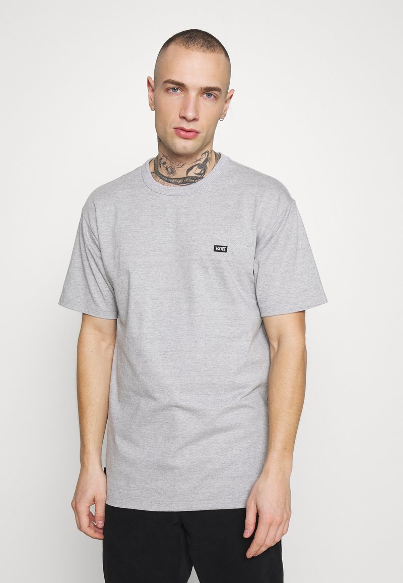 Camiseta de algodón gris con mangas cortas, escote redondo y un pequeño logo negro de Vans en el pecho. Textura suave y corte relajado.