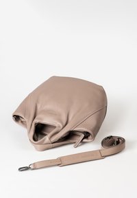 Borsa in pelle taupe con tracolla lunga removibile e chiusura con zip, posizionata su una superficie bianca.