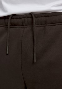 Svarta joggingsbyxor med elastisk midja, med en dragsko med svarta aglets. Mjuk tygkänsla, minimalistisk design.