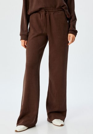 Pantalons larges marron en tissu doux avec une taille élastique et un cordon de serrage. Offre un ajustement ample et des poches latérales.
