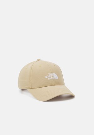 Beige baseball cap with a curved brim, made of fabric. Features white embroidered logo on the front and six ventilation holes.