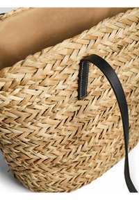 Cesto di paglia intrecciato di forma rotonda, colore naturale e manico in pelle nera con cuciture bianche. Fodera interna liscia color beige.