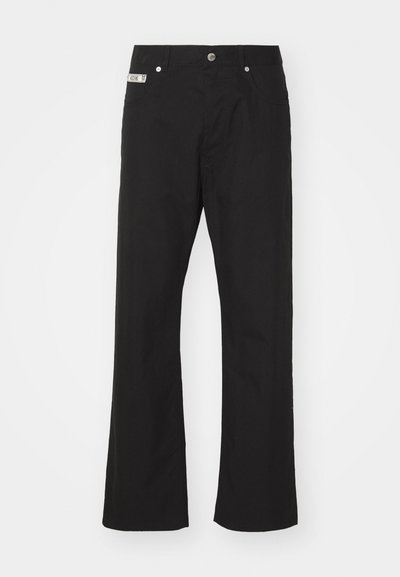 Juodos medvilnės kelnės su tiesiomis kojomis, su priekine mygtukų uždarymo sistema, dviem šoninėmis kišenėmis ir maža prekės ženklo etikete ant liemens.