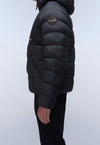Svart puffjacka med huva, med en texturerad, quiltad design, sidofickor med dragkedja och en logotyp i patchformat på vänster axel.