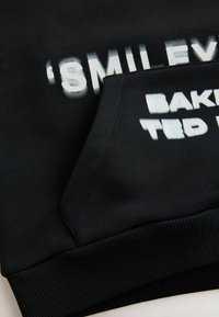 Sort sweatshirt med hvidt trykt tekst. Har hætte, ribstrikkede manchetter og sidelomme. Glat stof med let glans.