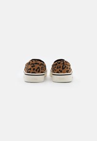 Leopardmönstrade slip-on skor i brunt och svart kanvas med en vit gummisula, med en logotyp präglad på hälen.