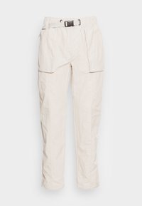 Pantaloni leggeri color beige chiaro, con vita elasticizzata, tasche laterali e chiusura frontale con fibbia. Presentano un tessuto texturizzato.