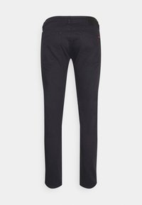 Jeans de mezclilla negra con corte recto, que cuentan con bolsillos traseros, un parche de cuero en la cintura y detalles de costura.